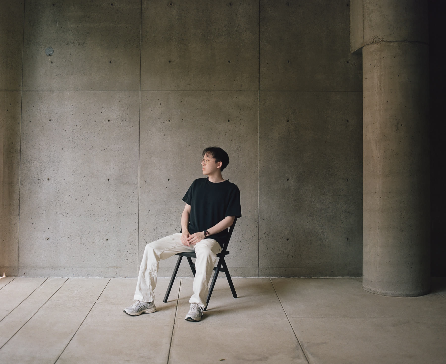 Jieming Wei seated in a concrete interior